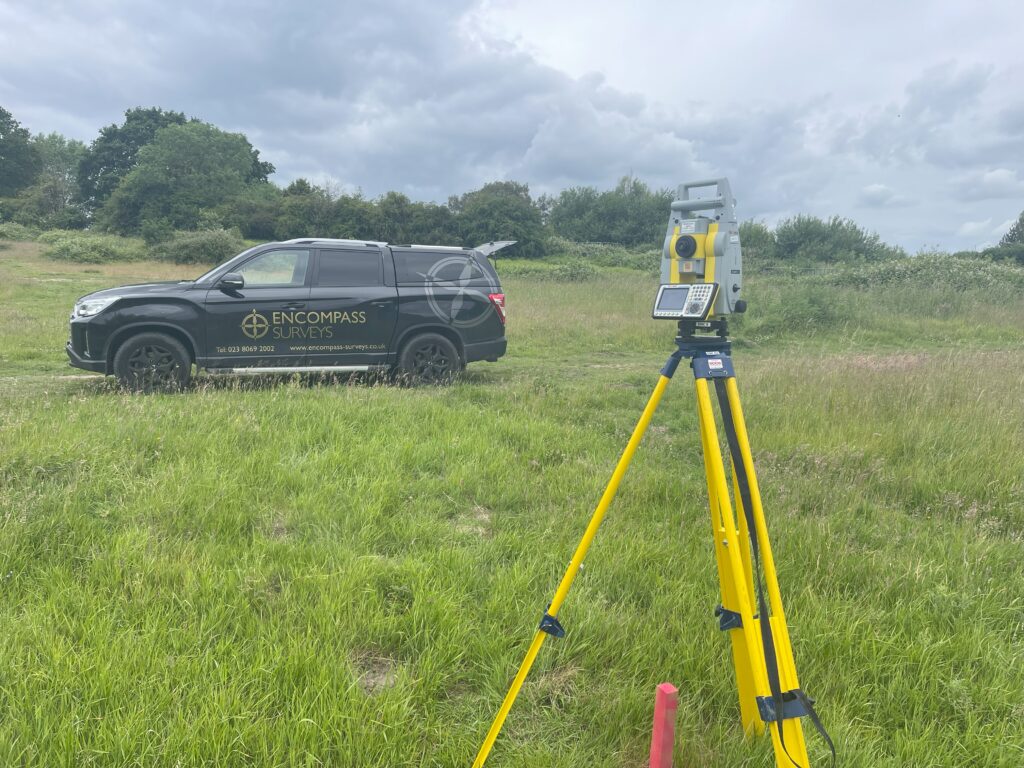 Photograph of Encompass Surveys Pickup Truck parked in field next to Total Station Surveying equipment