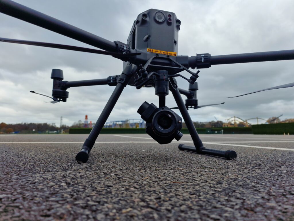 Picture of the DJI M300 Drone sat on tarmac with a theme park in the background