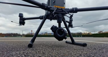 DJI m300 camera drone sat on the tarmac with a theme park visible in the background