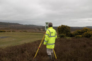 Photo of surveyor and total station in a field