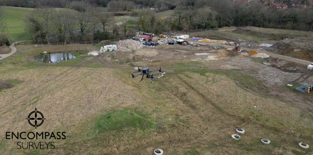 An aerial image of a DJI M350 drone in flight over a field / construction site