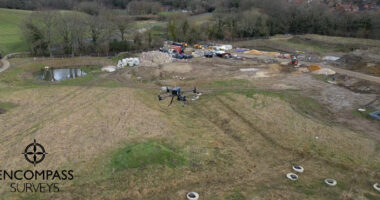 An aerial image of a DJI M350 drone in flight over a field / construction site